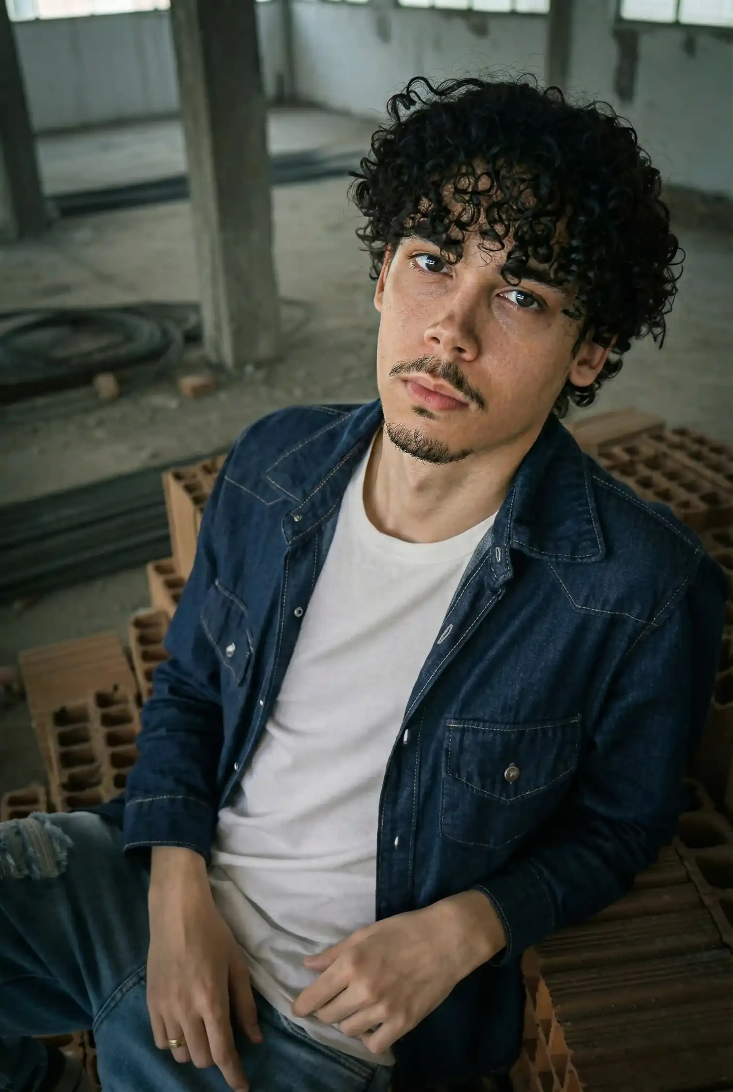 Bryan Haller em ensaio fotográfico editorial, sentado em uma construção